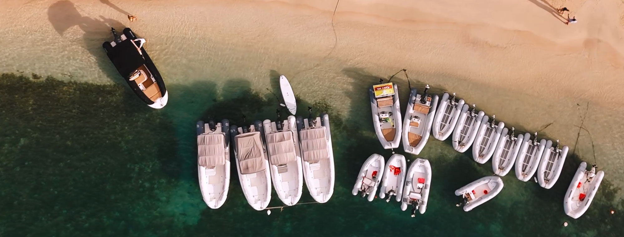 Aerial view of Wharfside Watersports' dinghy, Zodiac, and Medline rental boats lined up at the beach in Cruz Bay, St. John USVI